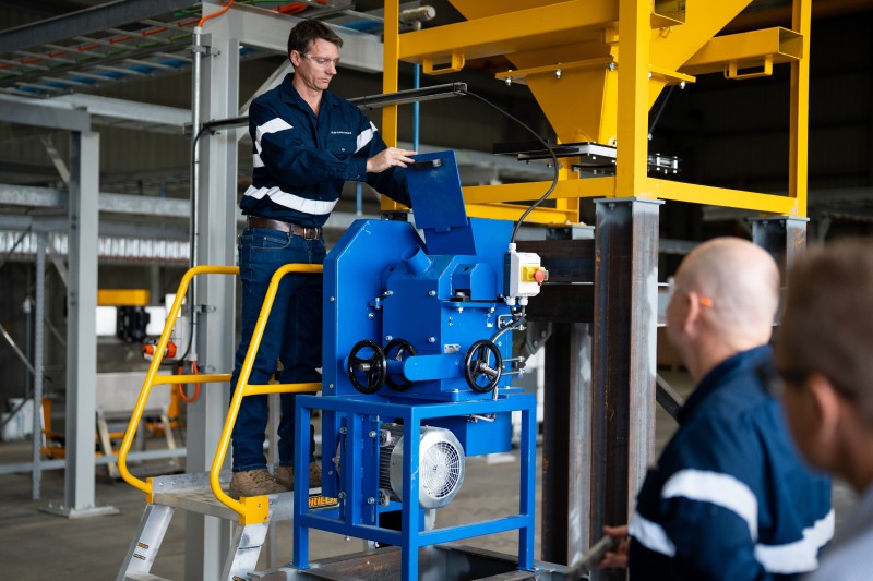 Two men standing beside a large blue and yellow machine
